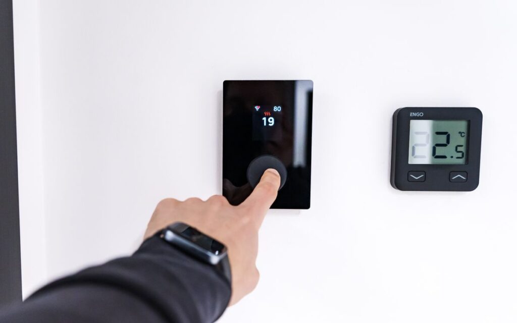 Hand adjusting a digital thermostat on a wall at home