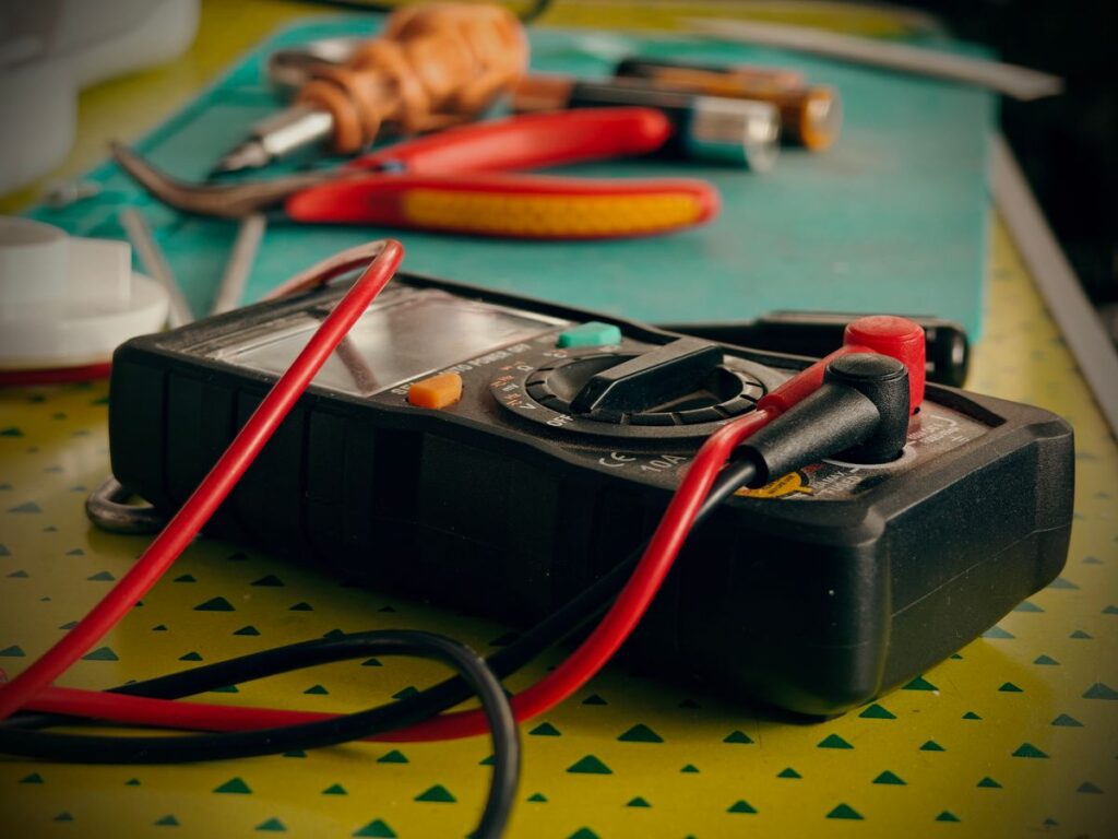 Multimeter and HVAC service tools laid out on a workbench