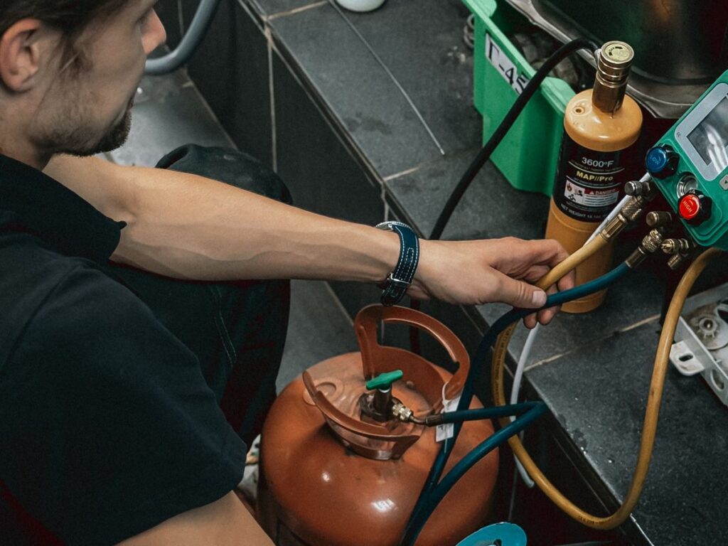 Technician working with refrigerant tanks and gauges on a commercial system