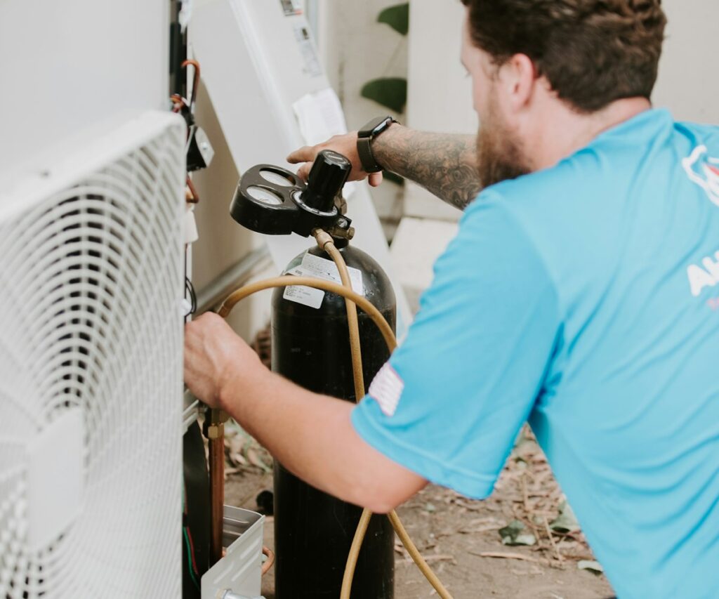 Technician in a work shirt servicing an outdoor air conditioner